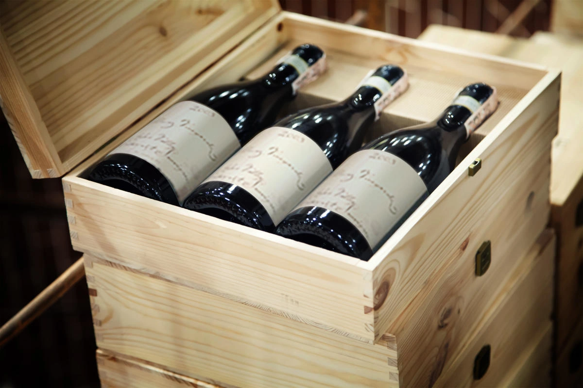 Three bottles of wine packed upright in an open wooden crate